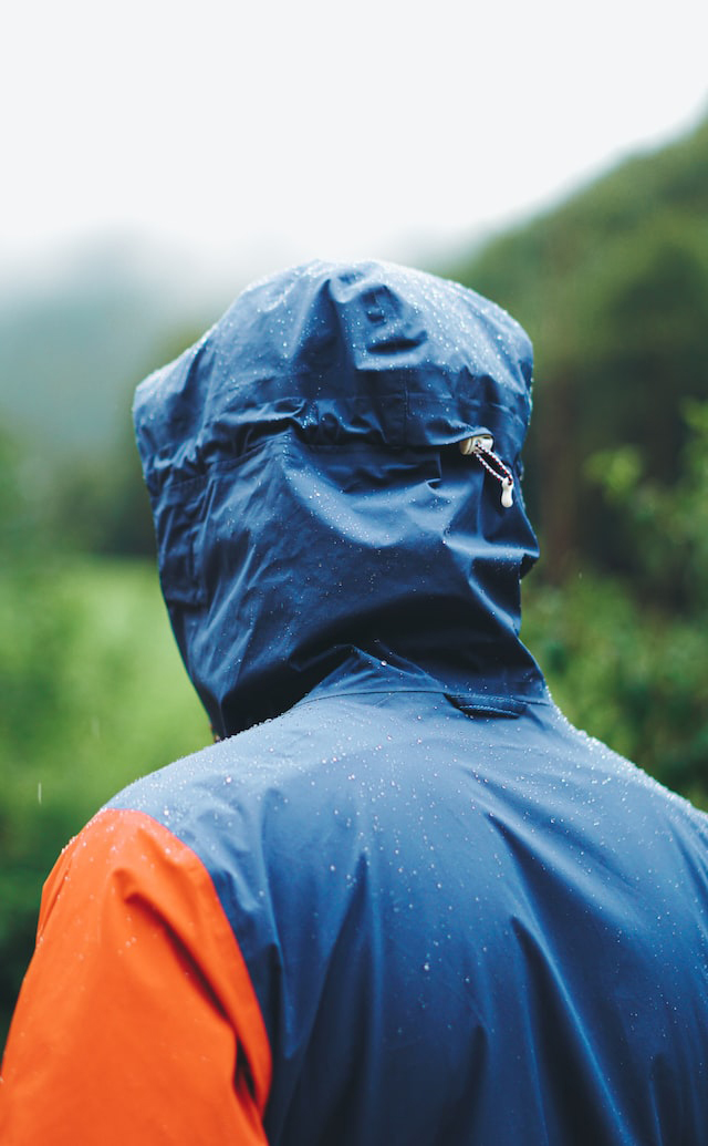A backside of a standing man while wears a raincoat
